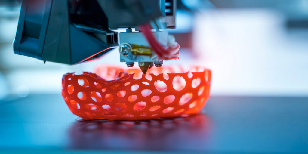 FDM-3D-Drucker druckt ein rotes Bauteil mit komplexer Gitterstruktur und Hohlräumen, die mit CNC-Bearbeitung nicht herstellbar wären
