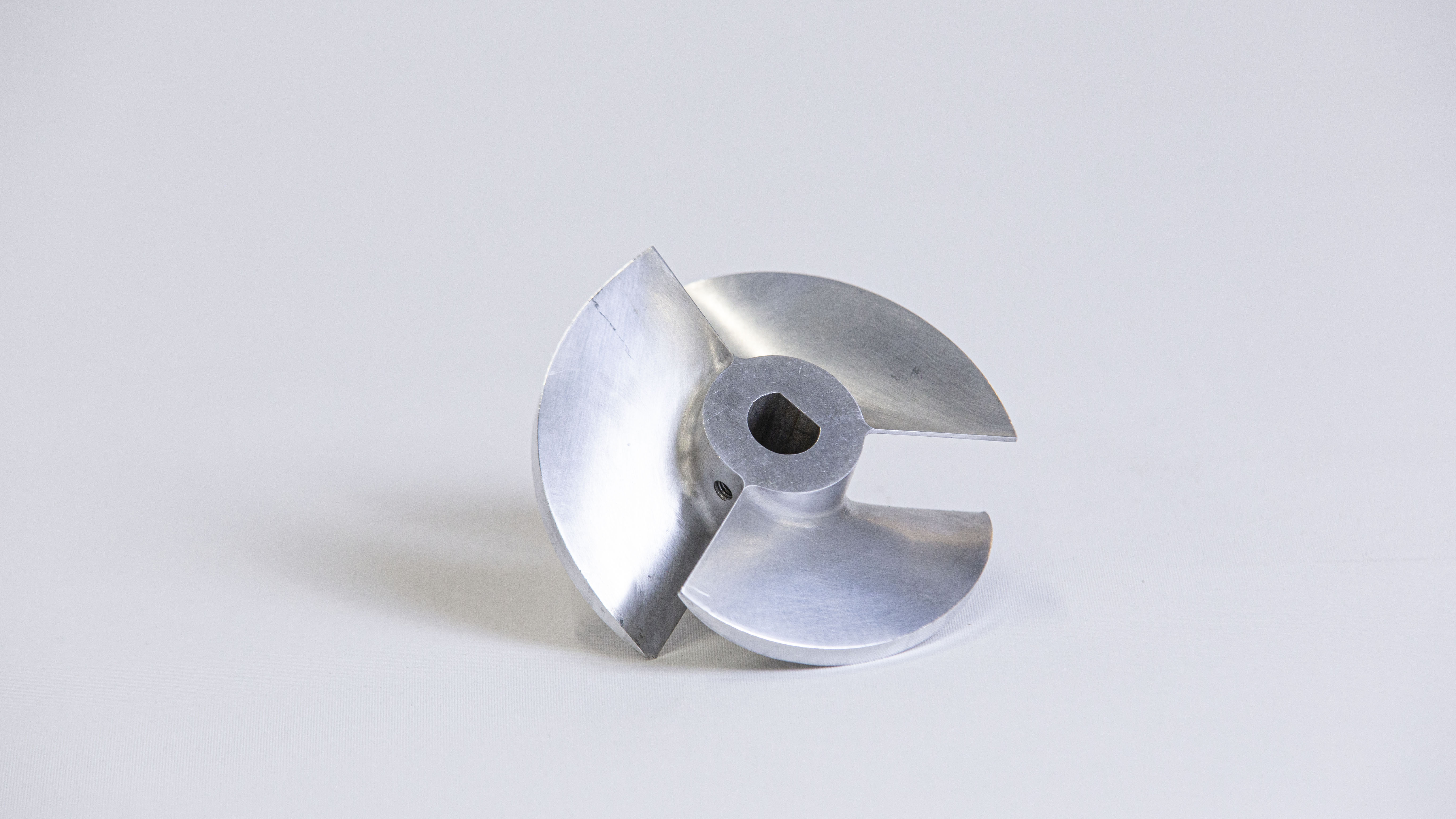 Roue métallique argentée fraisée CNC avec trois pales incurvées et un alésage d'arbre central avec rainure de clavette - Pièce de précision adaptée à la passivation des métaux pour le traitement anticorrosion