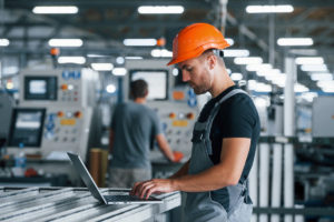 Arbeiter mit Laptop in Fabrikalle